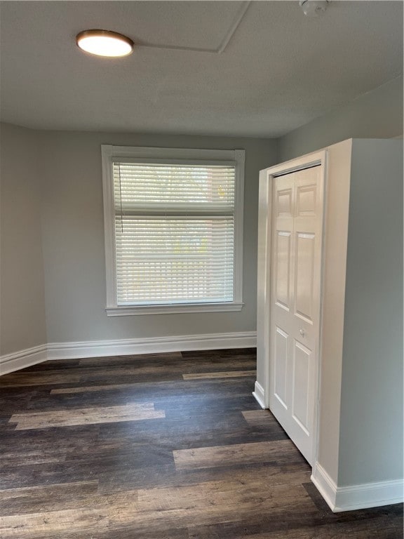 unfurnished bedroom with dark wood-type flooring and a closet