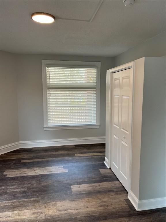 empty room featuring baseboards and dark wood-style floors