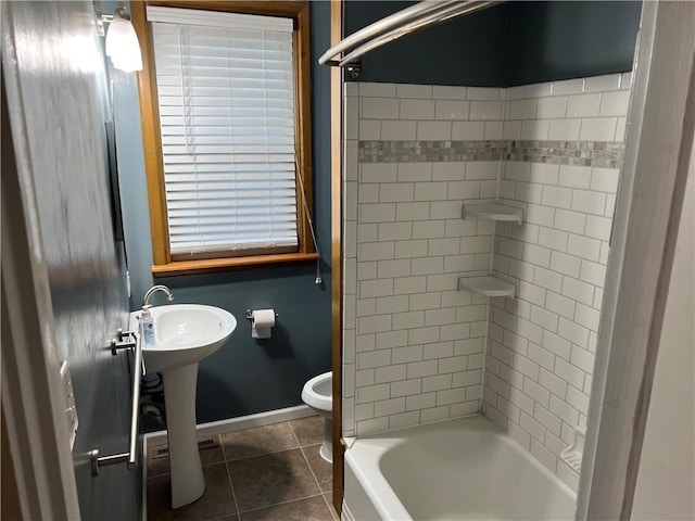 bathroom with baseboards, toilet, bathing tub / shower combination, tile patterned floors, and a sink