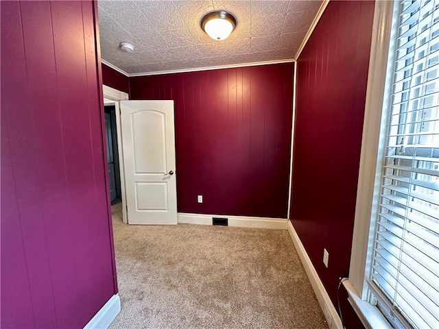 carpeted empty room featuring a textured ceiling, crown molding, and wood walls