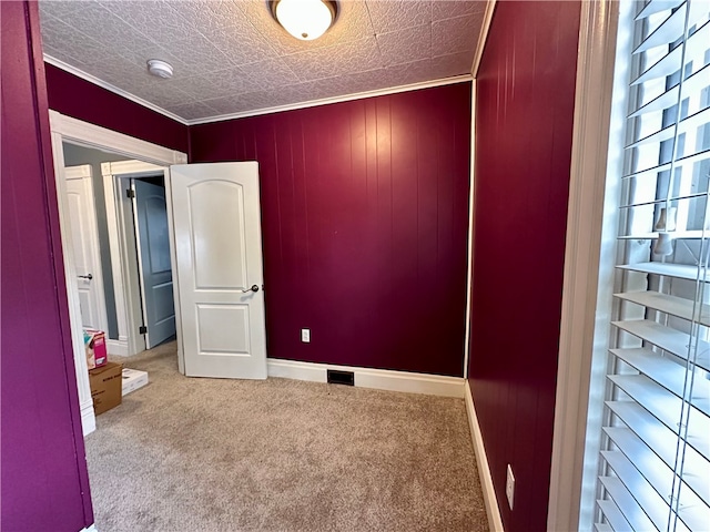 unfurnished room featuring a textured ceiling, light carpet, and ornamental molding