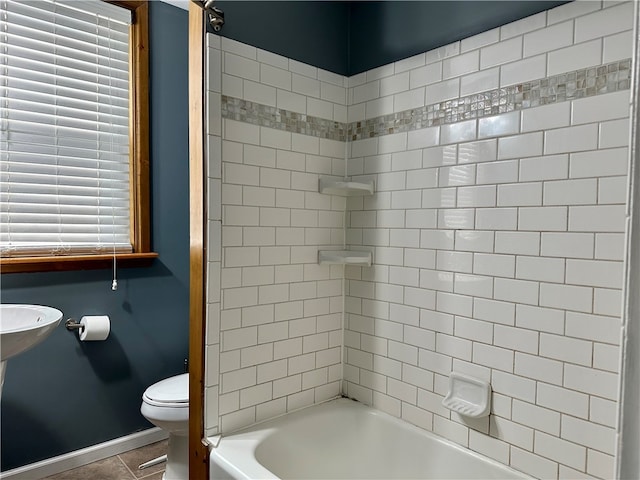 bathroom featuring tiled shower / bath combo, toilet, and tile patterned flooring