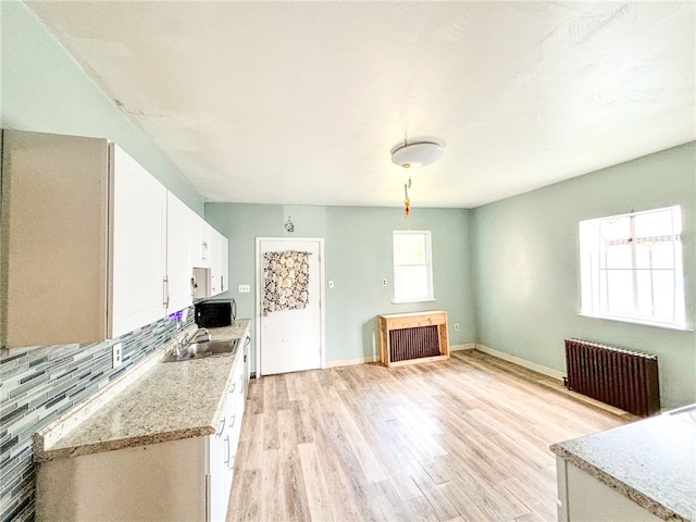 kitchen with radiator, white cabinetry, tasteful backsplash, and light hardwood / wood-style floors