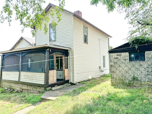 rear view of house with a sunroom and a yard