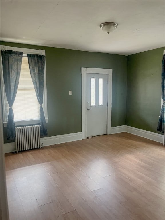 empty room featuring radiator heating unit and light wood-type flooring