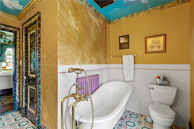 bathroom with a tub to relax in, tile walls, and toilet