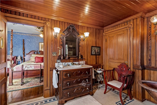 sitting room featuring wood walls, ornamental molding, sink, and wooden ceiling