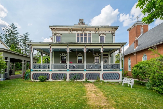 rear view of property with covered porch and a lawn