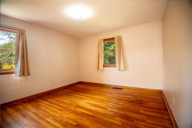 unfurnished room with a healthy amount of sunlight and hardwood / wood-style flooring