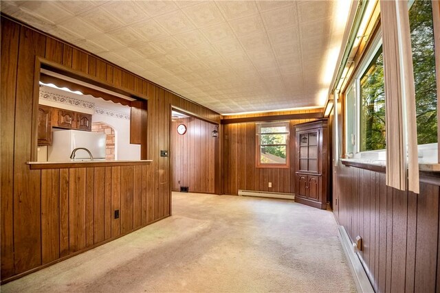 carpeted empty room featuring a baseboard heating unit and wooden walls