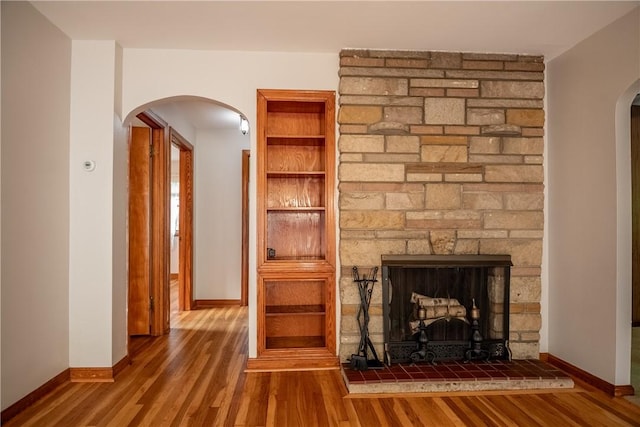 314 Lunn Blvd, Farrell, PA 16121 - unfurnished living room featuring arched walkways, baseboards, wood finished floors, and a stone fireplace