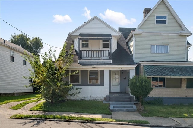 view of front of house featuring a chimney, a balcony, a shingled roof, and a front lawn