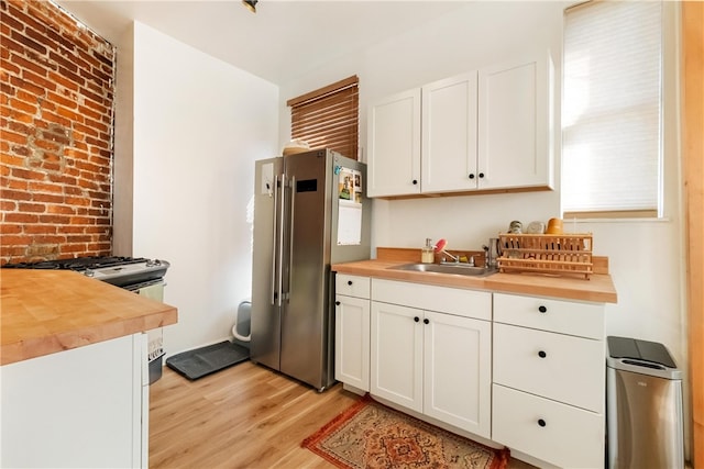 kitchen with light wood-type flooring, wooden counters, white cabinetry, and stainless steel appliances