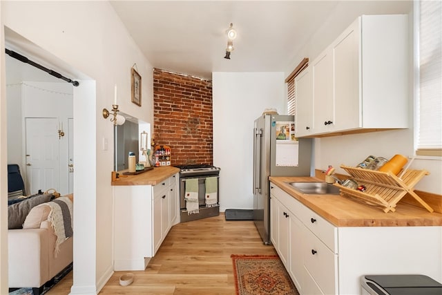 kitchen featuring gas range, butcher block countertops, white cabinets, and light hardwood / wood-style floors