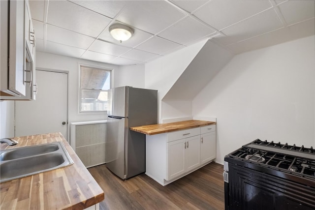 kitchen with white cabinetry, sink, stainless steel refrigerator, and wooden counters