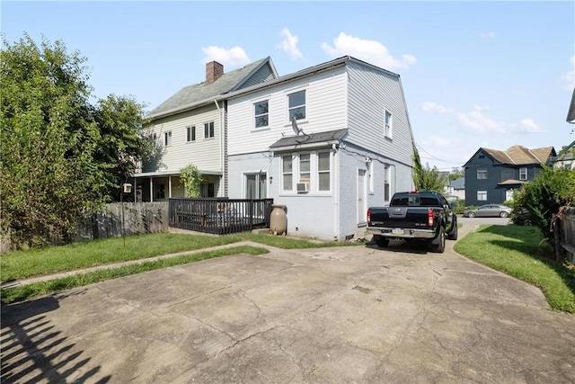 rear view of property with fence, a wooden deck, a chimney, and brick siding