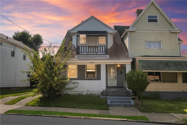 view of front of house featuring a balcony, a lawn, and covered porch