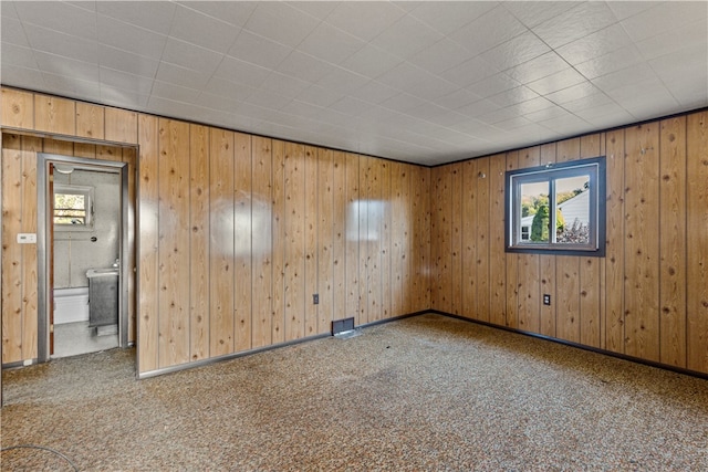 carpeted spare room with wood walls