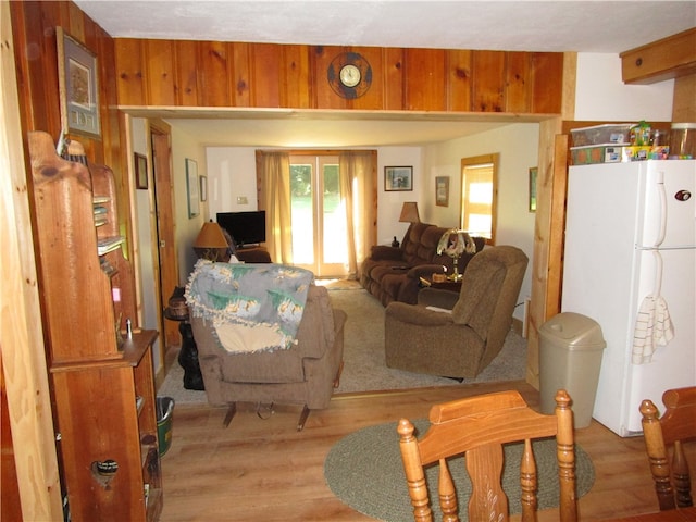 living room featuring light wood-type flooring and wood walls