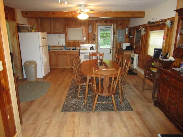 dining room featuring wooden walls, sink, ceiling fan, and light hardwood / wood-style floors