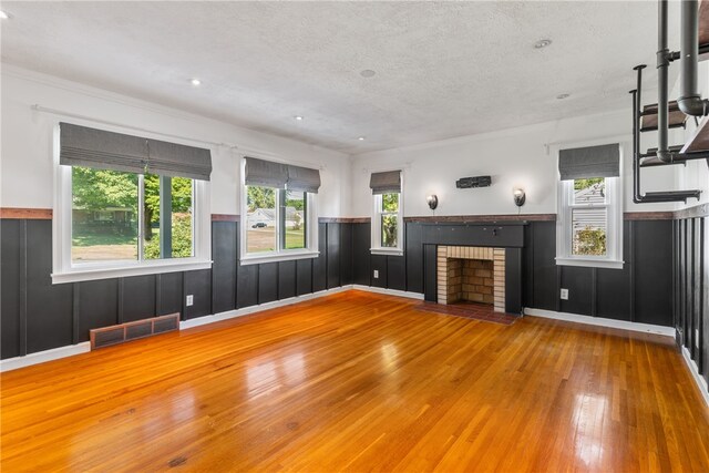 17 Long St, Hanover Twp Wsh, PA 15021 - unfurnished living room featuring wood-type flooring, a textured ceiling, a wainscoted wall, plenty of natural light, and a brick fireplace