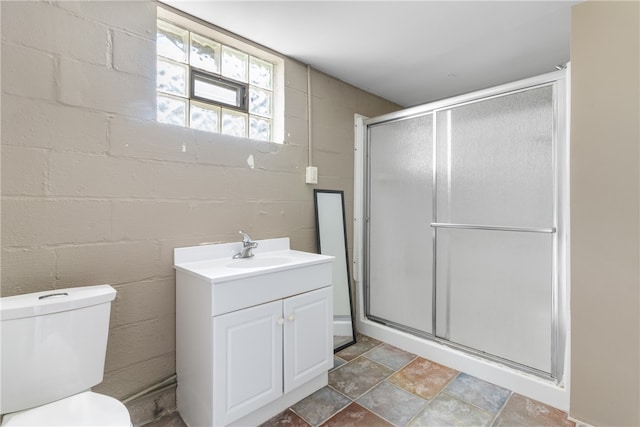 bathroom with toilet, vanity, and a shower with door