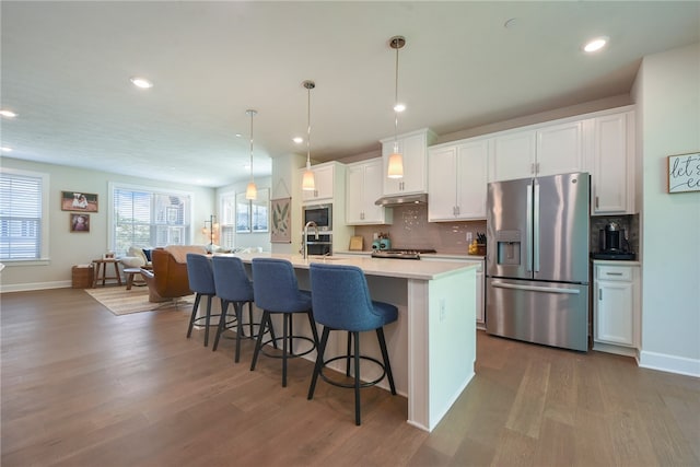 kitchen featuring dark wood-type flooring, appliances with stainless steel finishes, a center island with sink, and white cabinetry