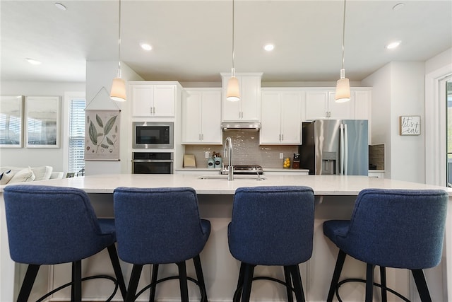 kitchen featuring hanging light fixtures, appliances with stainless steel finishes, sink, a large island, and a kitchen breakfast bar