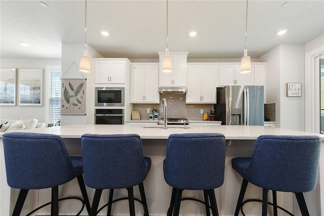 409 Spruce Ln, North Strabane, PA 15317 - kitchen with stainless steel appliances, under cabinet range hood, a sink, decorative backsplash, and light countertops