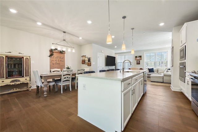 kitchen featuring white cabinets, sink, dark hardwood / wood-style floors, an island with sink, and pendant lighting