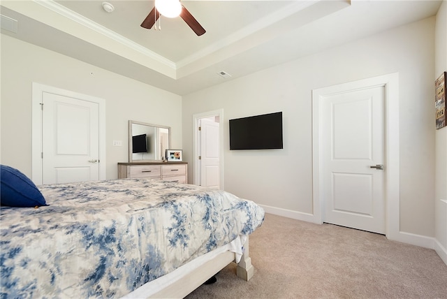 carpeted bedroom with ceiling fan, a raised ceiling, and ornamental molding