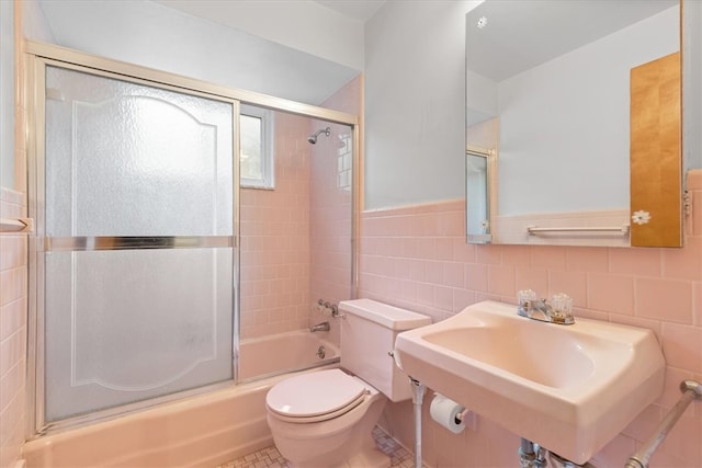 full bathroom featuring tile walls, tile patterned floors, shower / bath combination with glass door, sink, and toilet