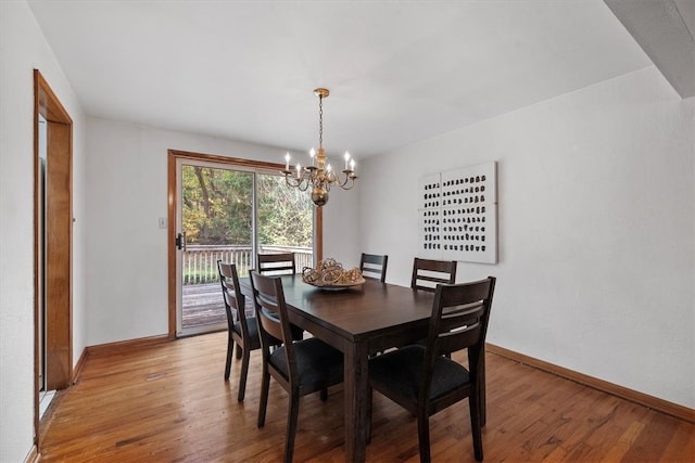 dining space with hardwood / wood-style flooring and an inviting chandelier