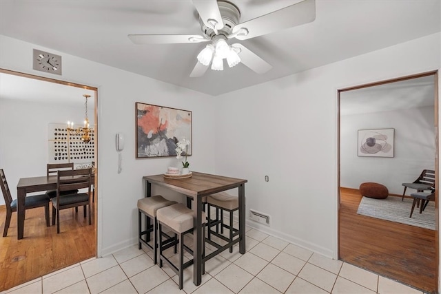 dining space with ceiling fan with notable chandelier and light hardwood / wood-style flooring