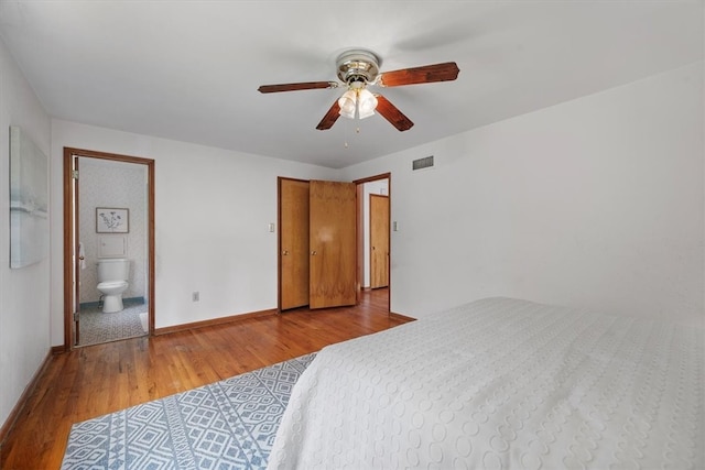 bedroom featuring ceiling fan, ensuite bath, and light wood-type flooring