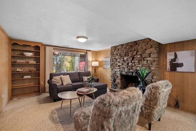 living room with a stone fireplace, wood walls, and light carpet