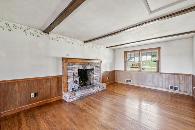 unfurnished living room featuring a fireplace, beamed ceiling, hardwood / wood-style flooring, and wooden walls