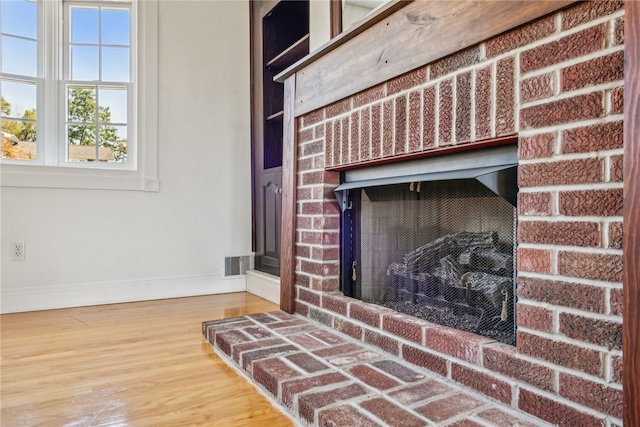 details with a brick fireplace and wood-type flooring