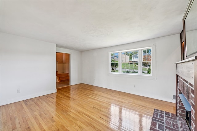 unfurnished living room featuring a brick fireplace and light hardwood / wood-style floors