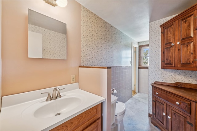 bathroom with vanity, tile walls, and toilet