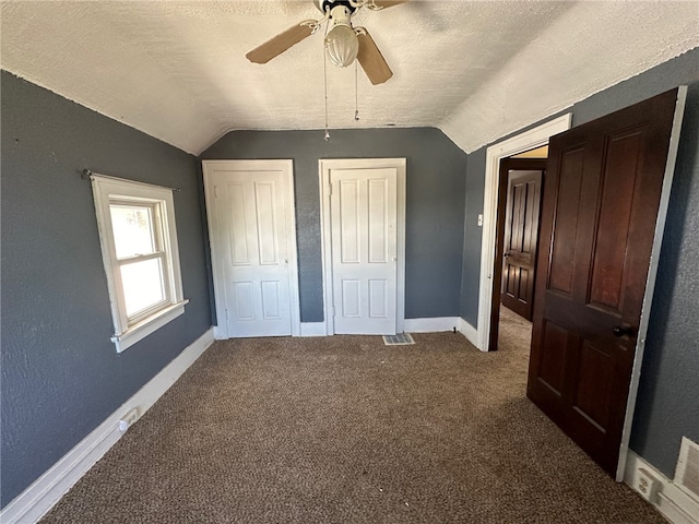 unfurnished bedroom with ceiling fan, carpet floors, a textured ceiling, and vaulted ceiling