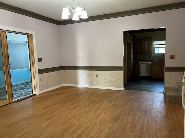 unfurnished room with baseboards, wood finished floors, a wainscoted wall, and a chandelier