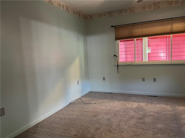 spare room featuring baseboards, carpet floors, and visible vents