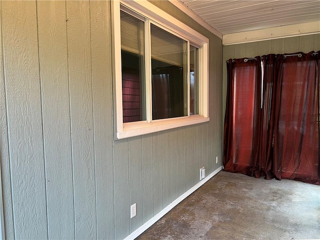 interior space featuring baseboards, unfinished concrete flooring, and wood walls