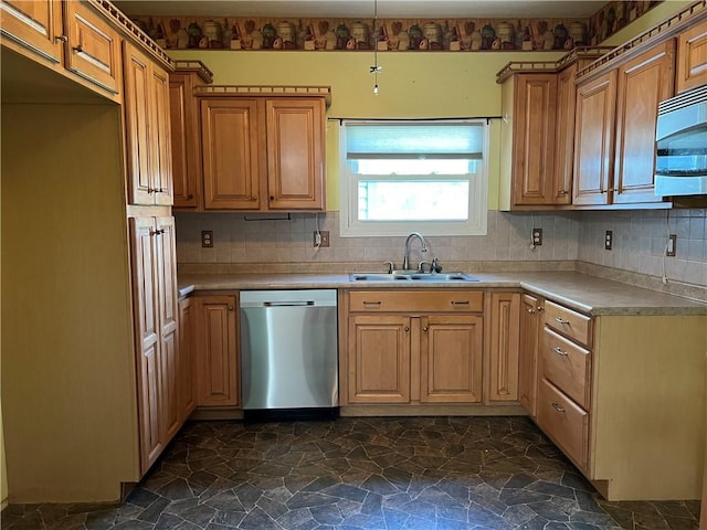 kitchen with a sink, light countertops, stone finish floor, appliances with stainless steel finishes, and backsplash