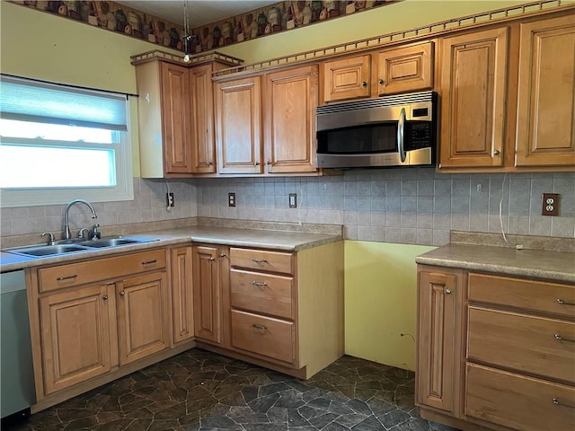 kitchen featuring a sink, stainless steel appliances, light countertops, stone finish floor, and tasteful backsplash