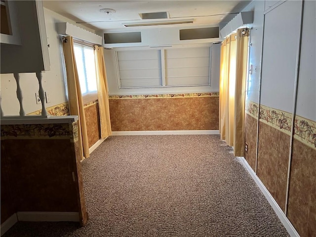 hallway featuring baseboards, carpet floors, wainscoting, and wallpapered walls