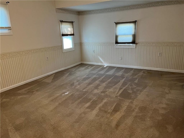 carpeted empty room featuring wainscoting