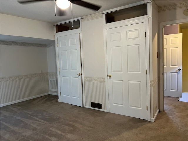 unfurnished bedroom featuring ceiling fan and dark colored carpet