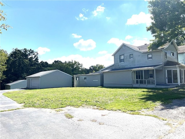 exterior space featuring a yard, a detached garage, and an outbuilding